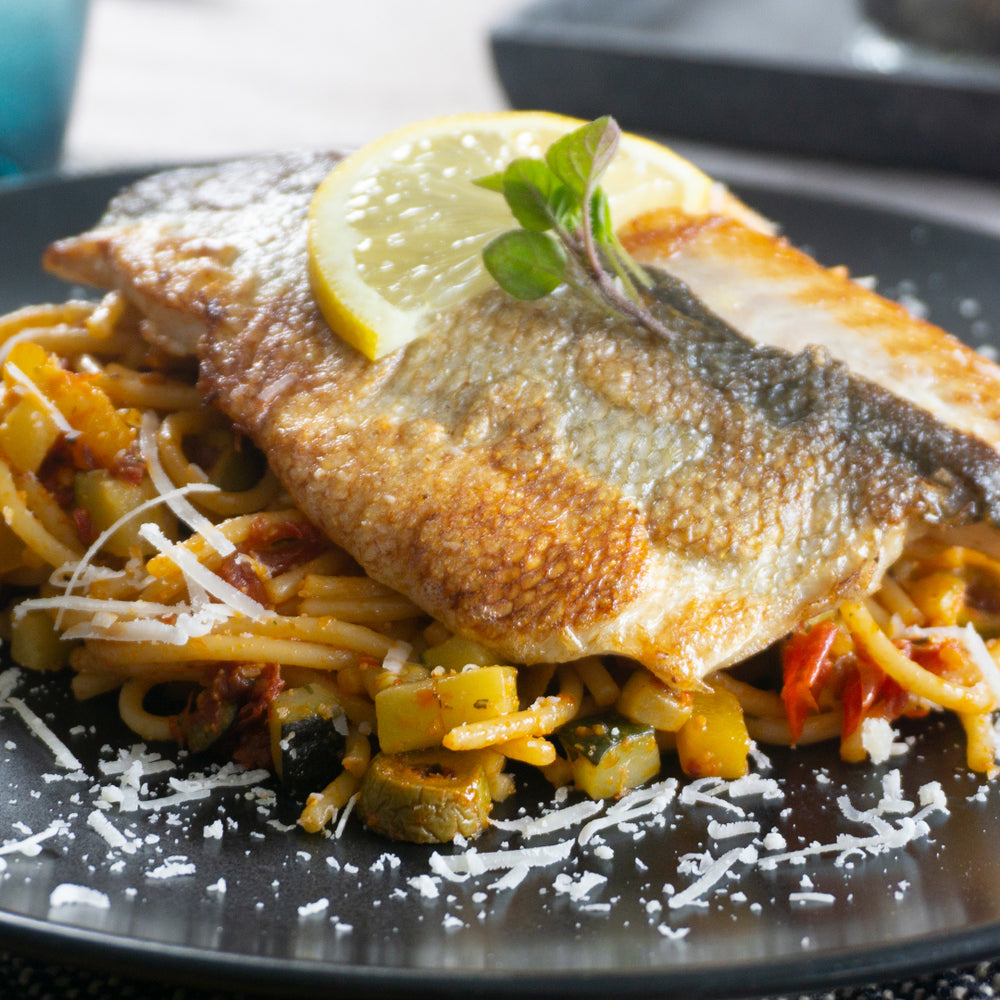 Wolfsbarschfilet auf mediterranen Spaghetti mit Parmesan