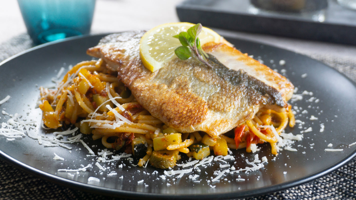 Wolfsbarschfilet auf mediterranen Spaghetti mit Parmesan